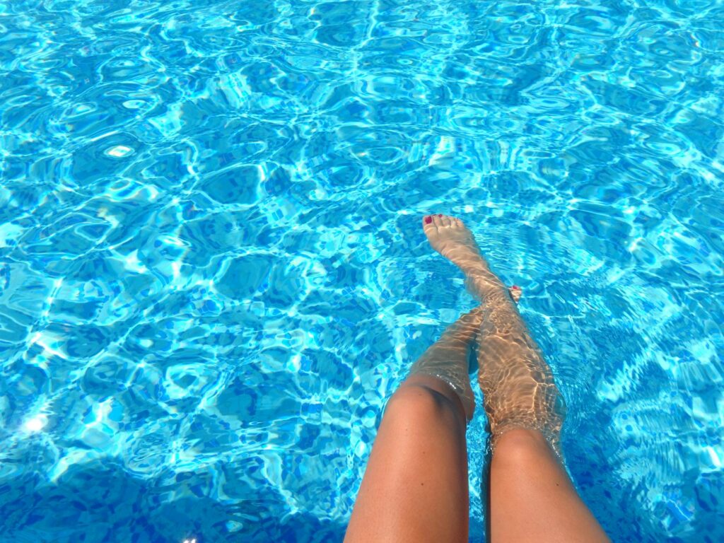 person feet dipping on pool