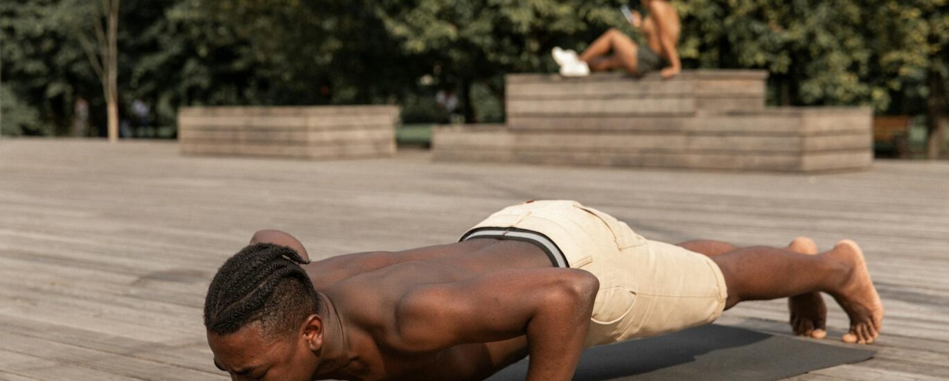 strong man practicing yoga in park