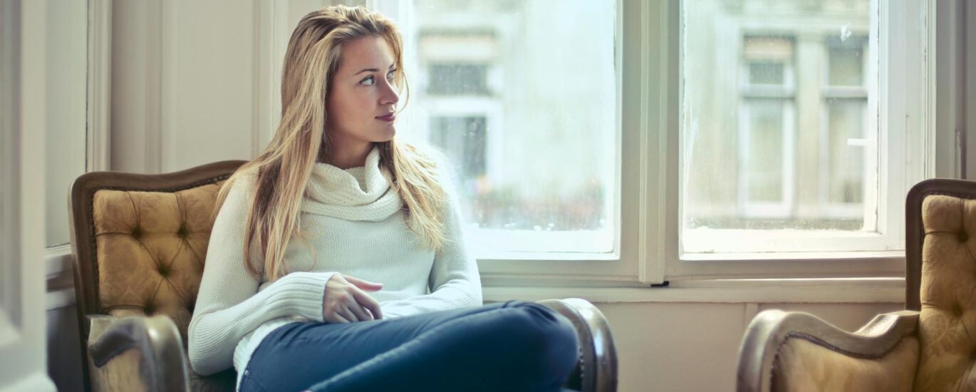 photography of woman sitting on chair near window