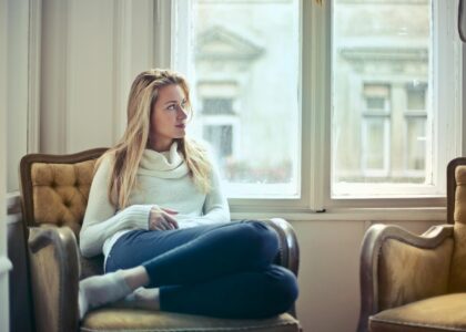 photography of woman sitting on chair near window